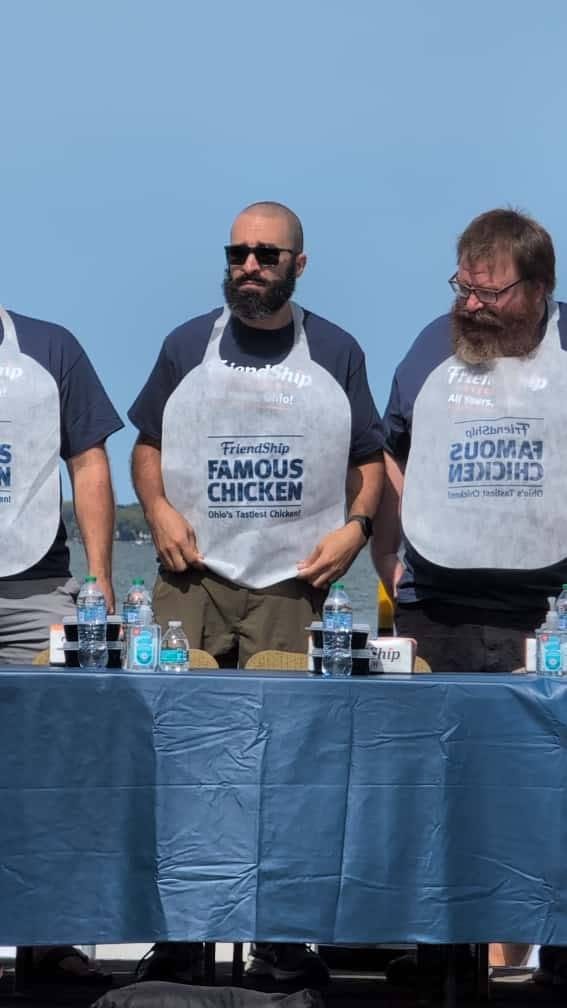 Abe at a competitors’ table in a contest bib, water bottles lined up in front of him, another competitor alongside.